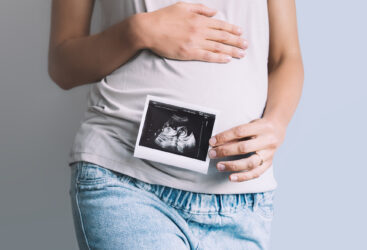 Kobieta w ciąży trzymająca zdjęcie USG przy brzuchu