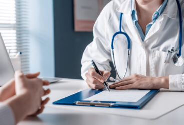 Kobieta rozmawia z lekarzem, który robi notatki.
