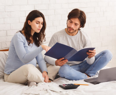 Kobieta w ciąży siedzi na łóżku razem z mężczyzną